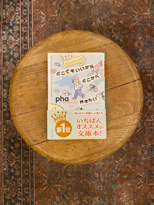 Cover of pha's essay collection, photographed on a wooden stool